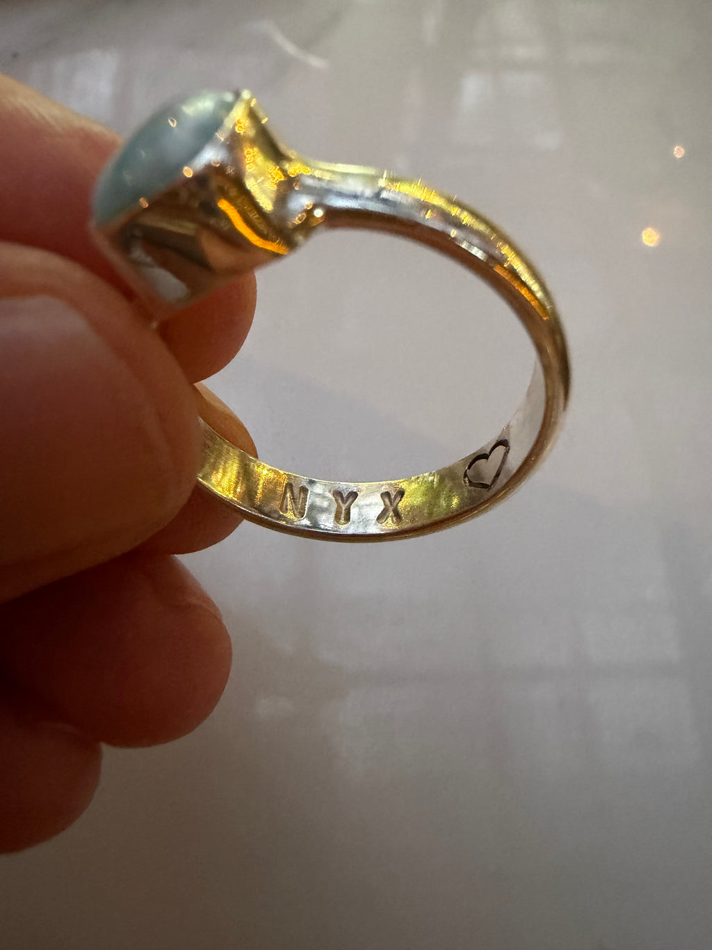Gold ring with a gemstone held in a hand against a light background