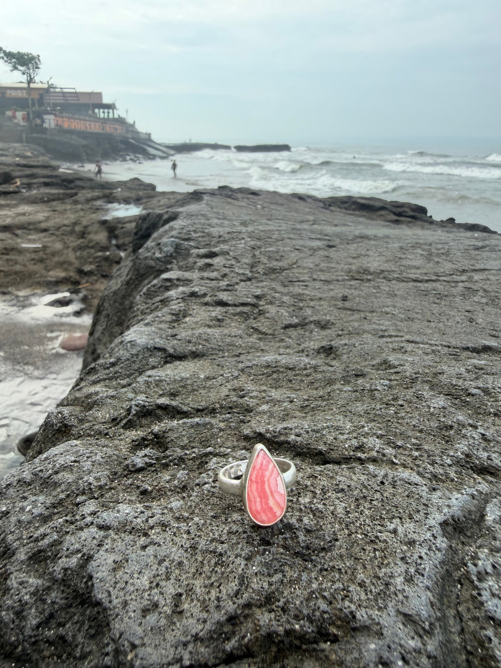 Ring with a pink stone on a rock by a body of water