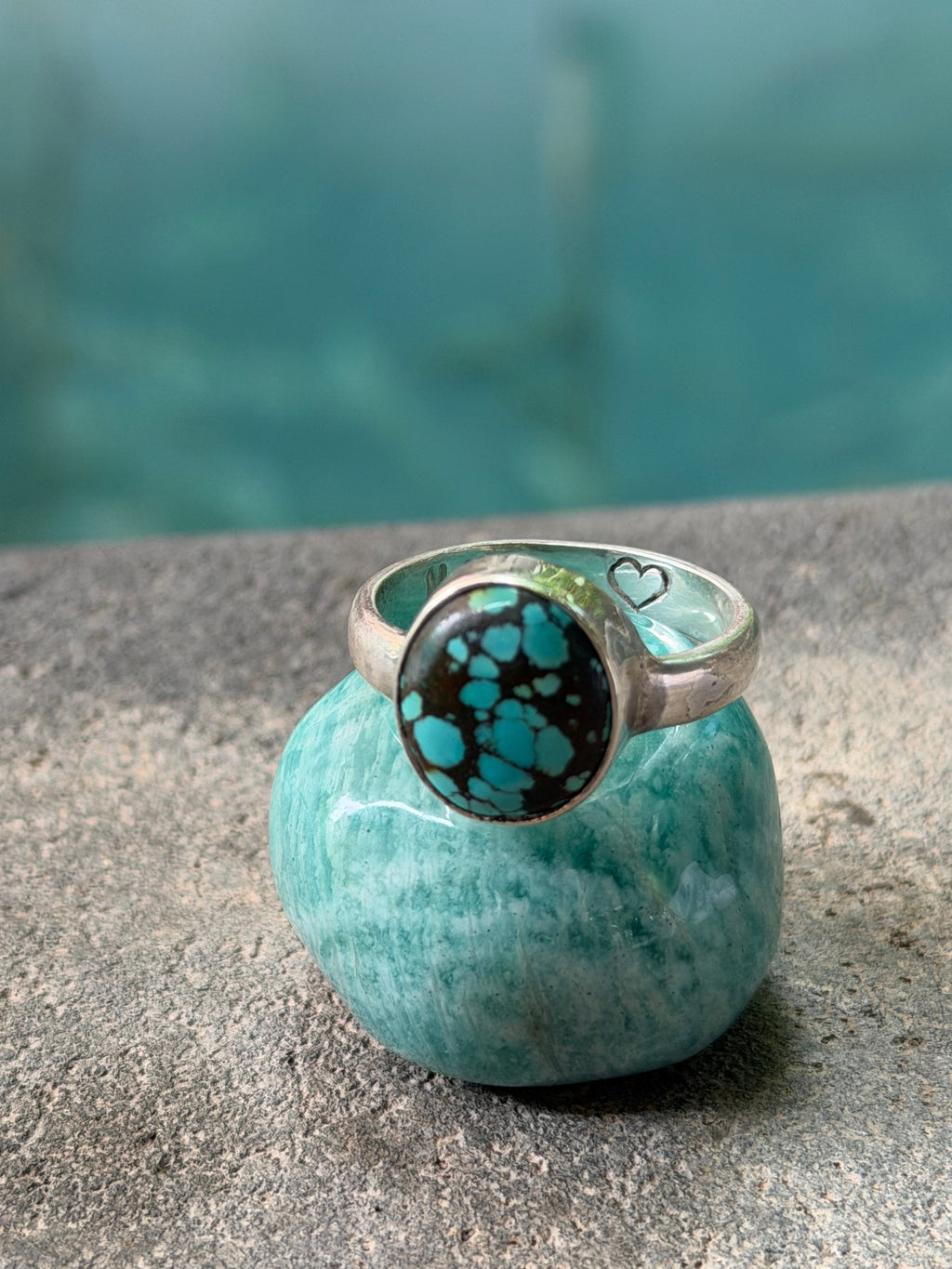 Turquoise stone ring with silver band on a concrete surface