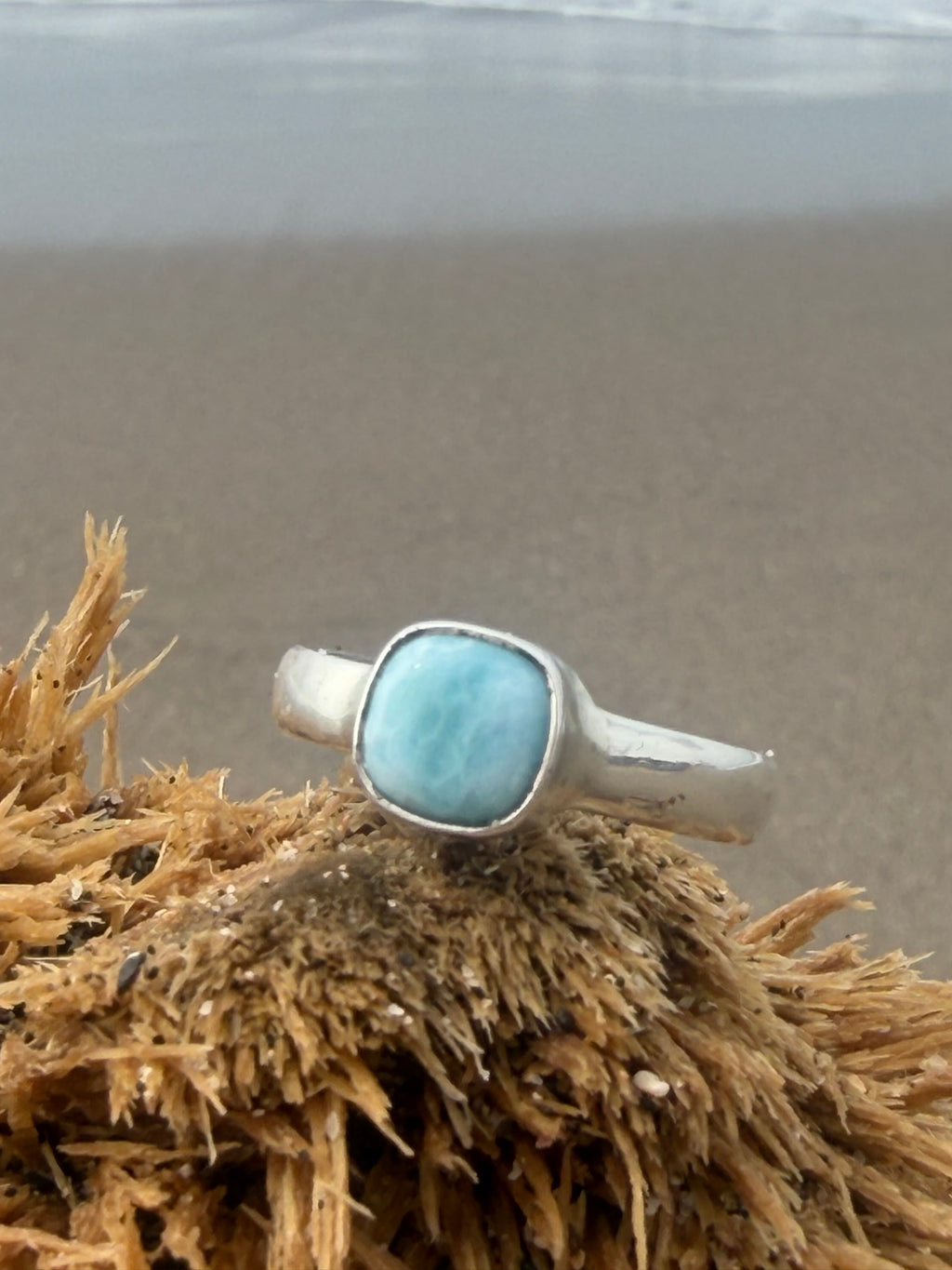 Silver ring with a Larimar stone on a textured surface